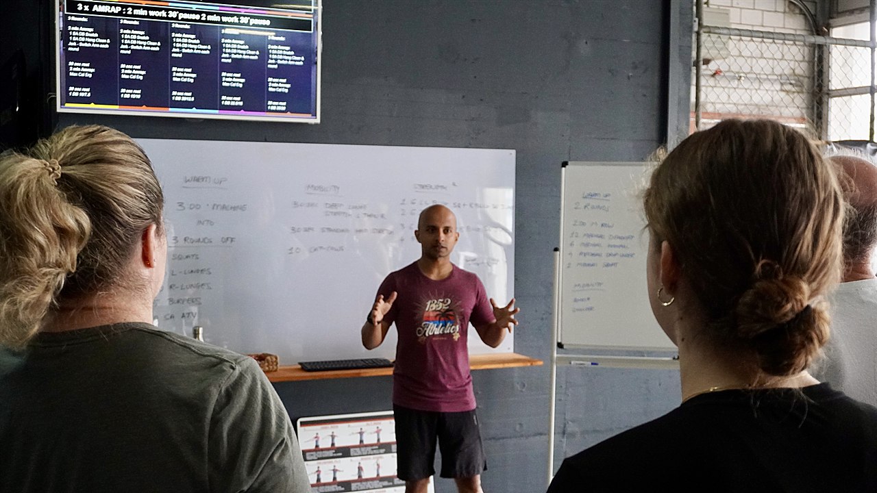 Coach Vineet explaining the workout at the whiteboard